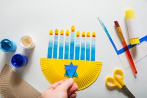 paper craft for kids. person makes diy hanukkah candle holder. create art for children